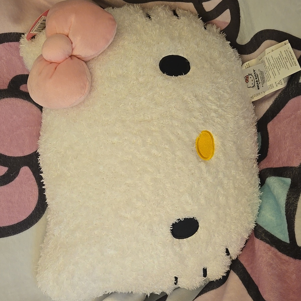 This is a white Hello Kitty sherpa-like decorative pillow with a pink bow